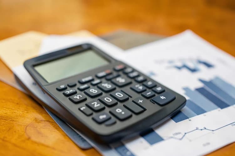 Uma calculadora e gráficos financeiros sobre uma mesa, representando a apuração de haveres em um contexto empresarial.