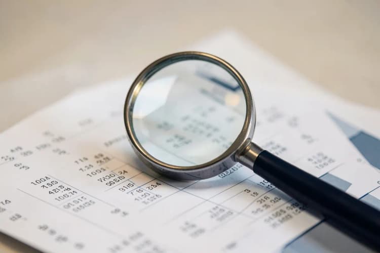 Uma lupa examinando um documento com números e gráficos.